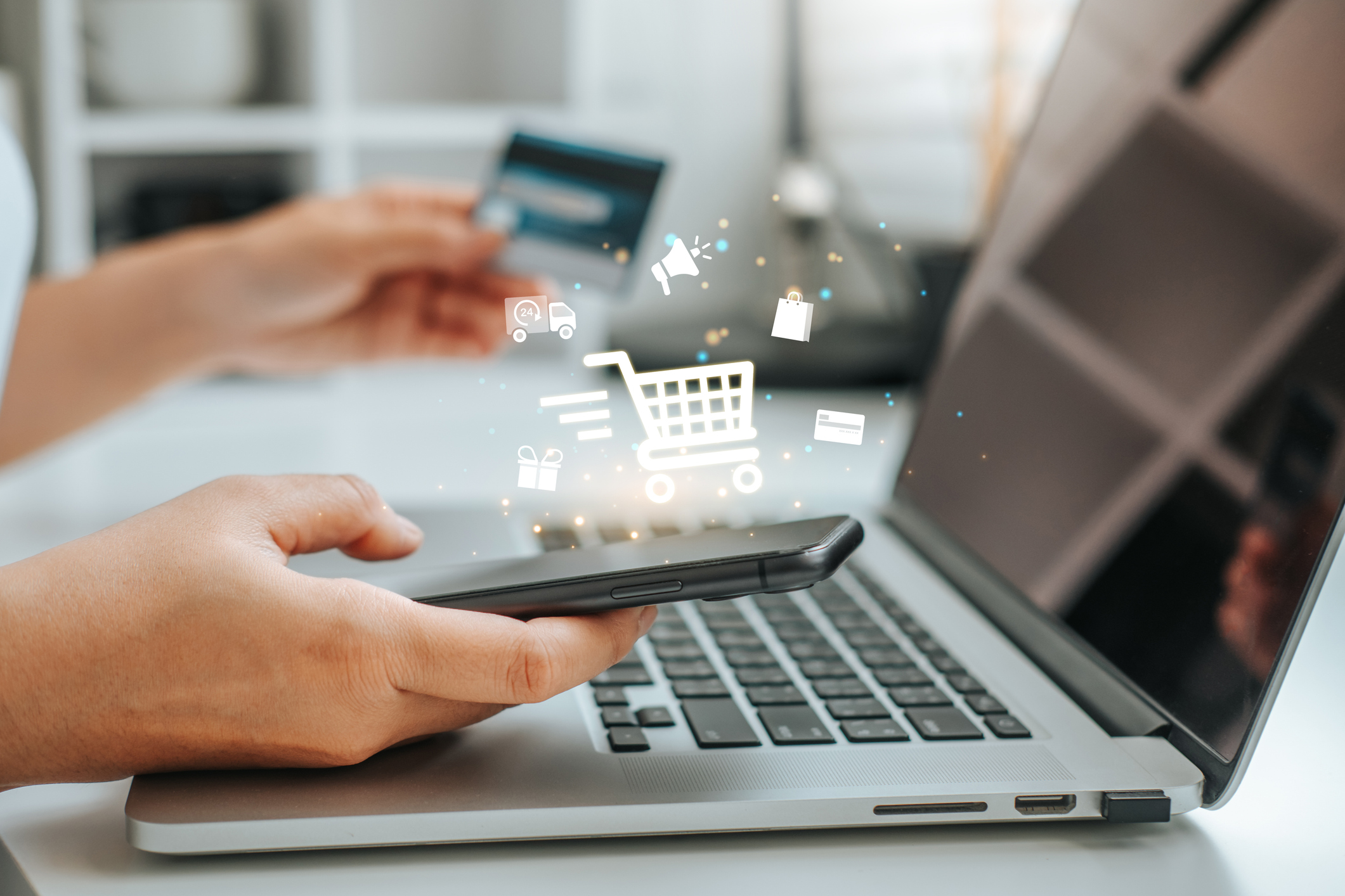 Marketing trends scene featuring an open laptop, a credit card, a smart phone, and the image of a shopping cart.